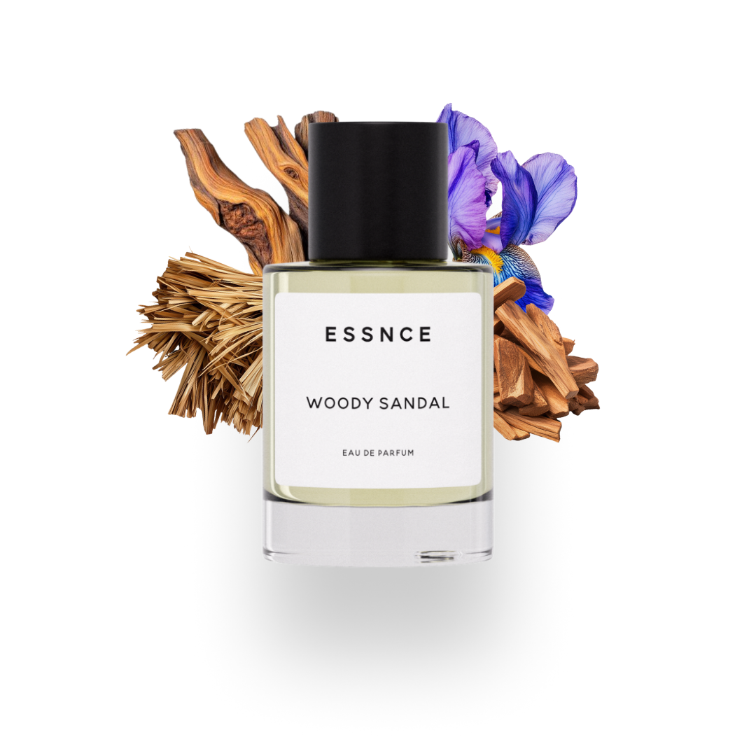 En flaska ESSNCE Woody sandal Eau de Parfum visas med en svart kork och en vit etikett. Bakom flaskan finns ingredienser som cederträ, sandelträ, iris och papyrus.